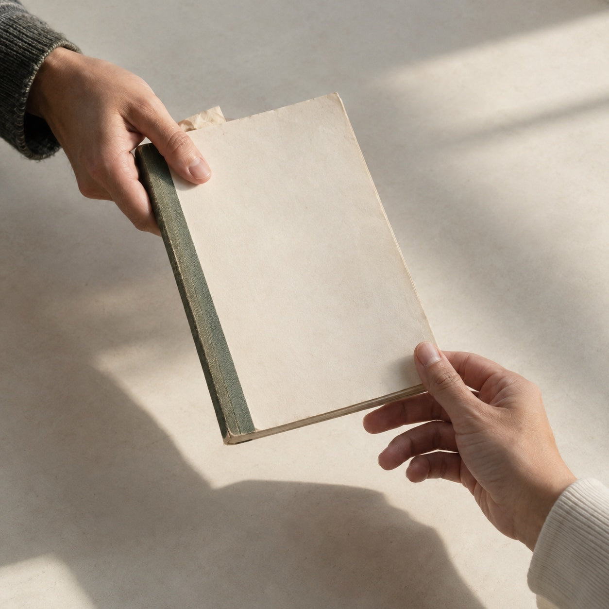 two hands passing a book from one person to another