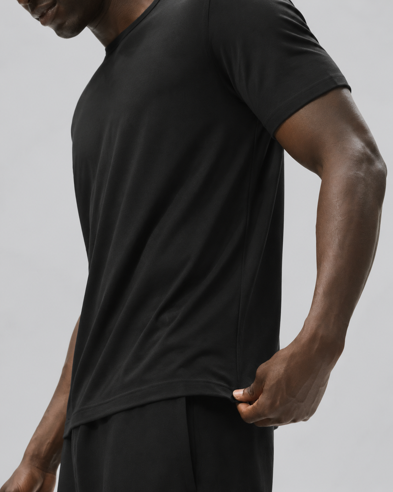 Close side view of the Black Relaxed Tee, with a hand holding the straight hem.