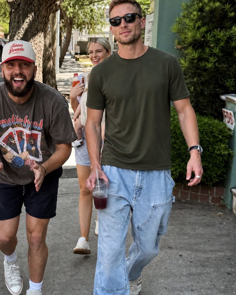 Model wearing a pine green relaxed tee and jeans while walking with friends.