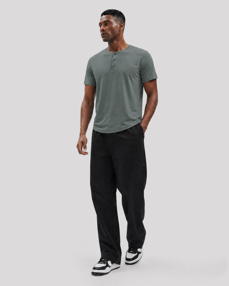 Full-length studio view of the Bamboo green Henley with black trousers.