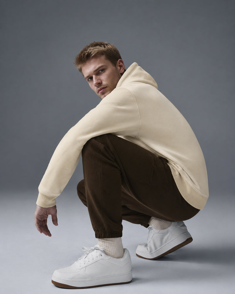 Model crouching in TexTale hoodie in Butter