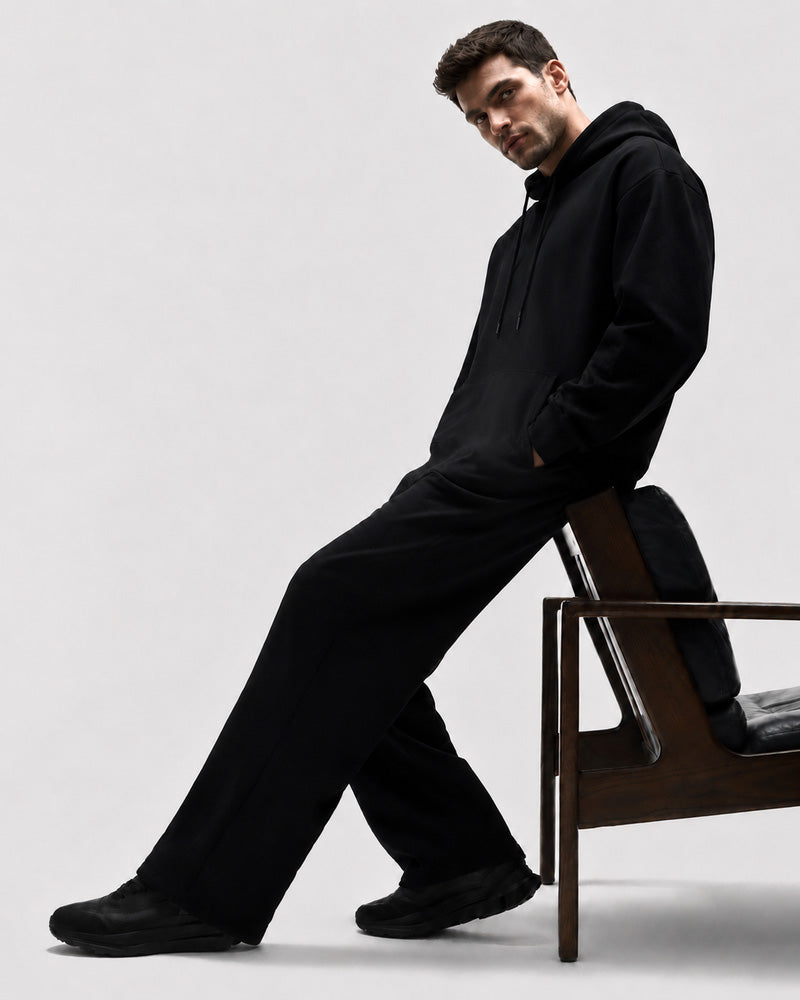 Model leaning against a chair in the TexTale Rain-Repel Hoodie in Black