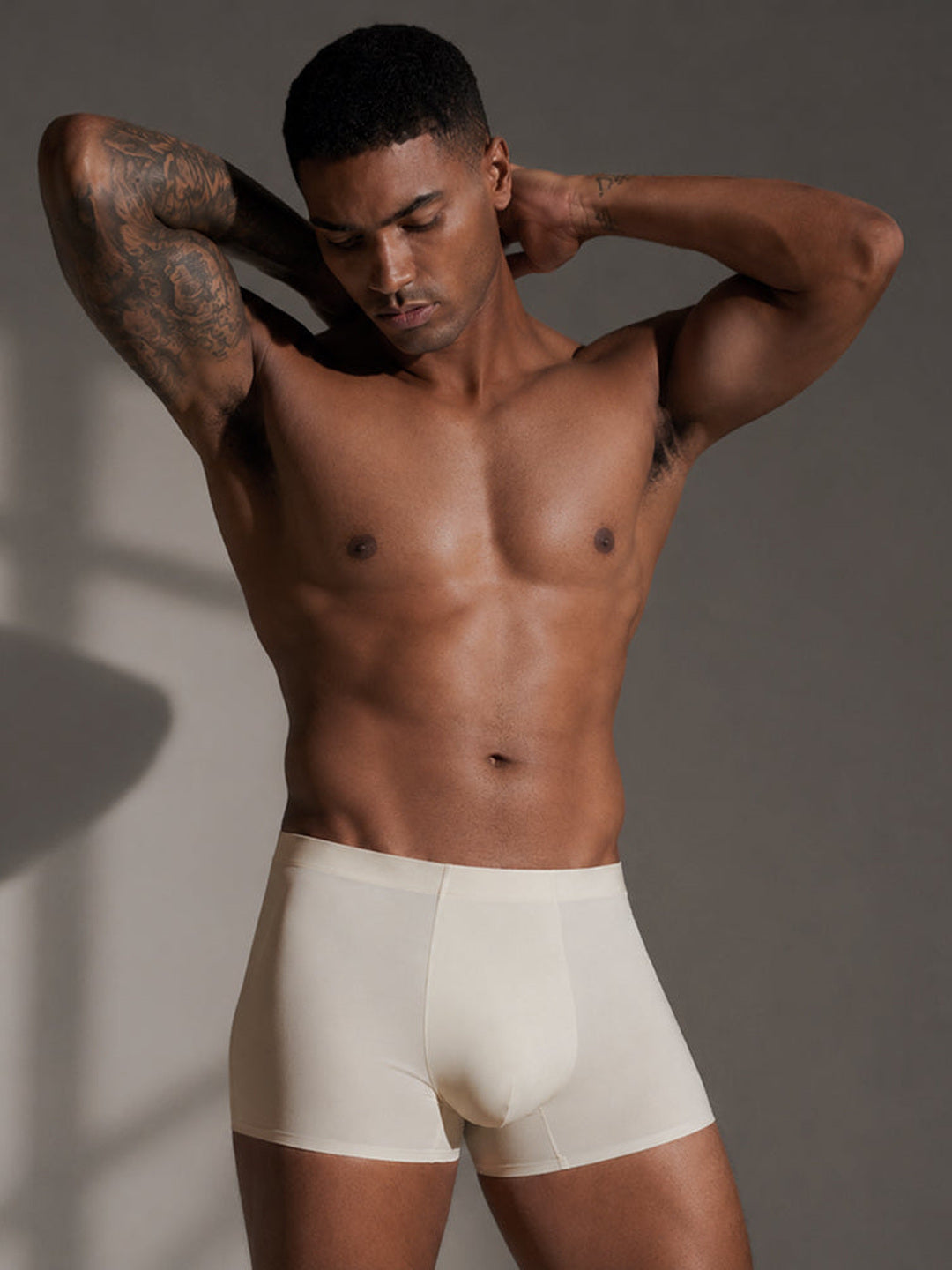 A model wearing the cream Airy Trunk, both hands behind his head