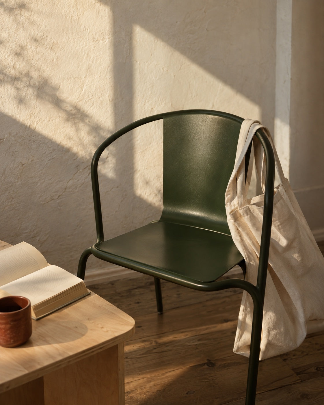 a green chair, cotton tote and an open book in afternoon light